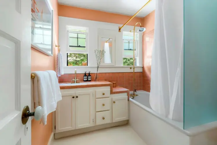 Bathroom with orange tiles, bathtub, and sink at Charming Walk Street Hideaway in Venice Beach by Open Air Homes.