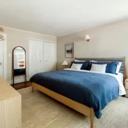 Bedroom with wooden bed, blue bedding, and wooden dresser at Charming Walk Street Hideaway by Open Air Homes.