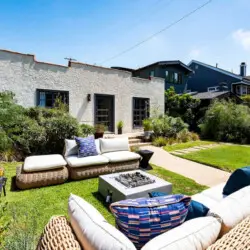 Outdoor seating area with wicker furniture and fire pit in garden at Charming Walk Street Hideaway in Venice Beach by Open Air Homes.