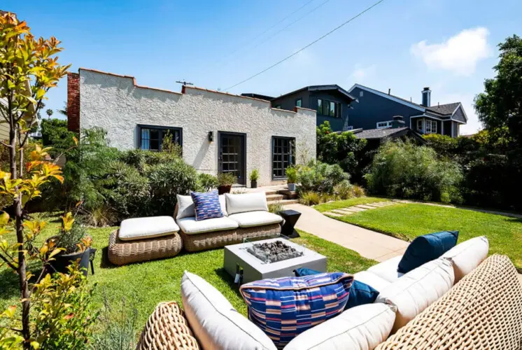 Outdoor seating area with wicker furniture and fire pit in garden at Charming Walk Street Hideaway in Venice Beach by Open Air Homes.