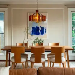 Dining area with wooden table and chairs, hanging light, and view of living room at Charming Walk Street Hideaway in Venice Beach by Open Air Homes.