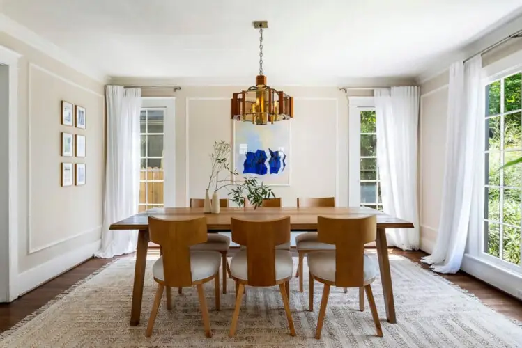 Dining room with wooden table, chairs, and chandelier at Charming Walk Street Hideaway in Venice Beach by Open Air Homes.