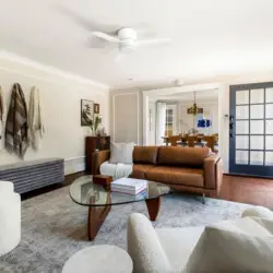 Living area with leather sofa, glass coffee table, and wall-mounted TV at Charming Walk Street Hideaway in Venice Beach by Open Air Homes.