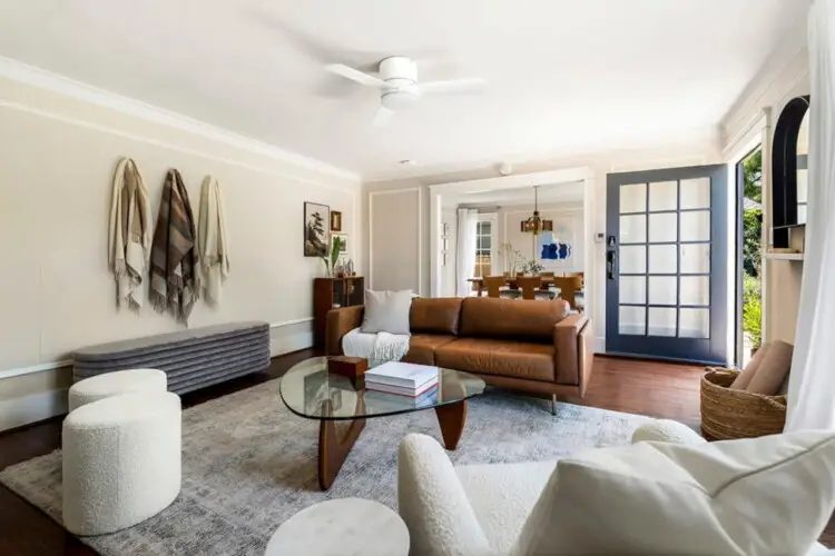 Living area with leather sofa, glass coffee table, and wall-mounted TV at Charming Walk Street Hideaway in Venice Beach by Open Air Homes.