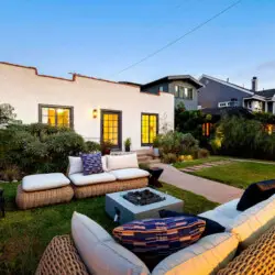 Outdoor seating area with wicker furniture and fire pit at Charming Walk Street Hideaway in Venice Beach by Open Air Homes.