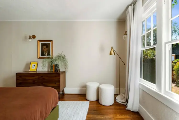 Bedroom with white ceiling, bed, and drBedroom with white ceiling, bed, brown bedding, wooden dresser, and window at Charming Walk Street Hideaway in Venice Beach by Open Air Homes.esser at Charming Walk Street Hideaway - by Open Air Homes