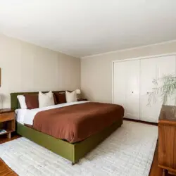 Bedroom with bed, brown bedding, nightstands, and wooden dresser at Charming Walk Street Hideaway in Venice Beach by Open Air Homes.