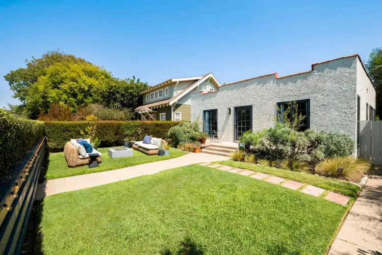 Outdoor seating area with wicker furniture in garden at Charming Walk Street Hideaway in Venice Beach by Open Air Homes.