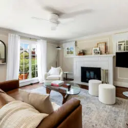 Living area with leather sofa, glass coffee table, fireplace, and wall-mounted TV at Charming Walk Street Hideaway in Venice Beach by Open Air Homes.