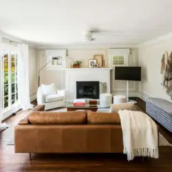 Living area with leather sofa, fireplace, and wall-mounted TV at Charming Walk Street Hideaway in Venice Beach by Open Air Homes.