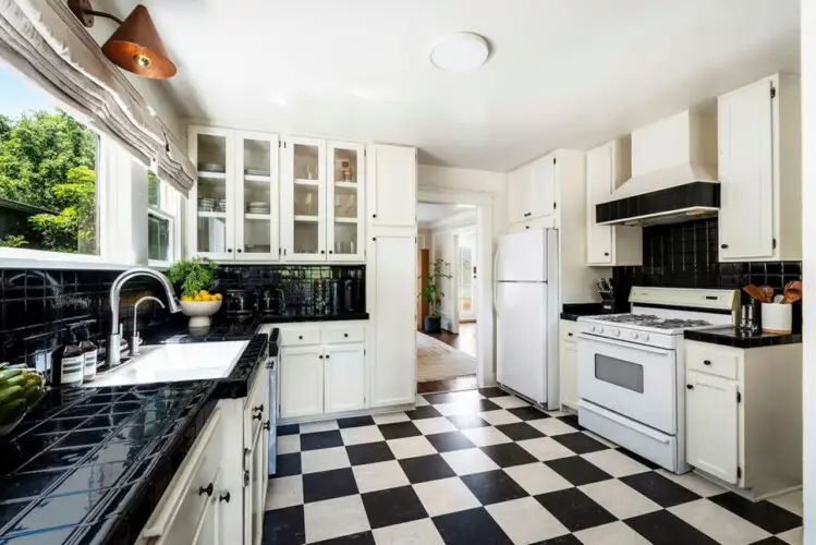 Kitchen with black and white checkered flooring, white cabinets, and window at Charming Walk Street Hideaway in Venice Beach by Open Air Homes.