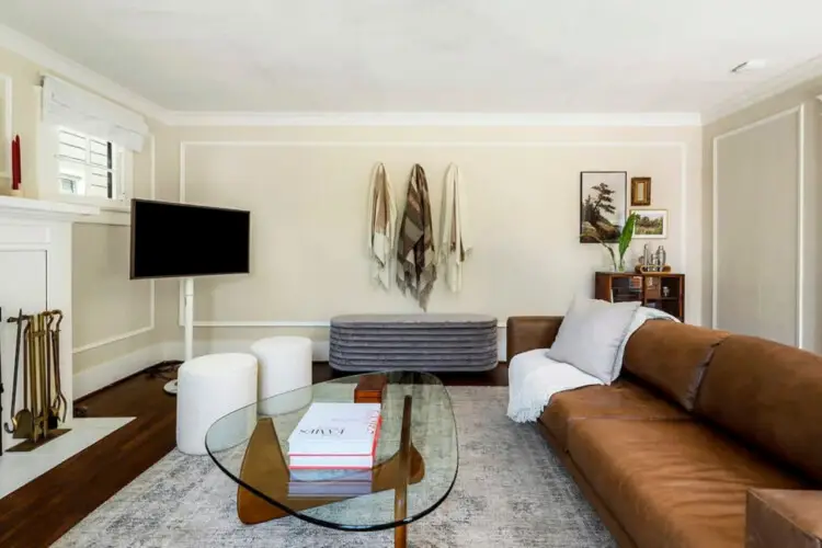 Living area with leather sofa, glass coffee table, and wall-mounted TV at Charming Walk Street Hideaway in Venice Beach by Open Air Homes.