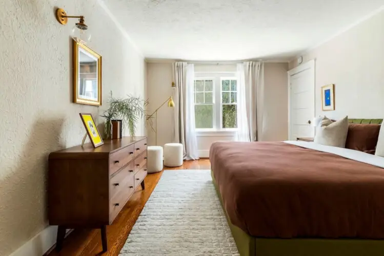 Bedroom with wooden dresser, bed, and window at Charming Walk Street Hideaway in Venice Beach by Open Air Homes.