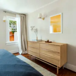 Bedroom with dresser, mirror, and window at Charming Walk Street Hideaway by Open Air Homes.