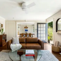 Living area with leather sofa, glass coffee table, and view of dining area at Charming Walk Street Hideaway in Venice Beach by Open Air Homes.