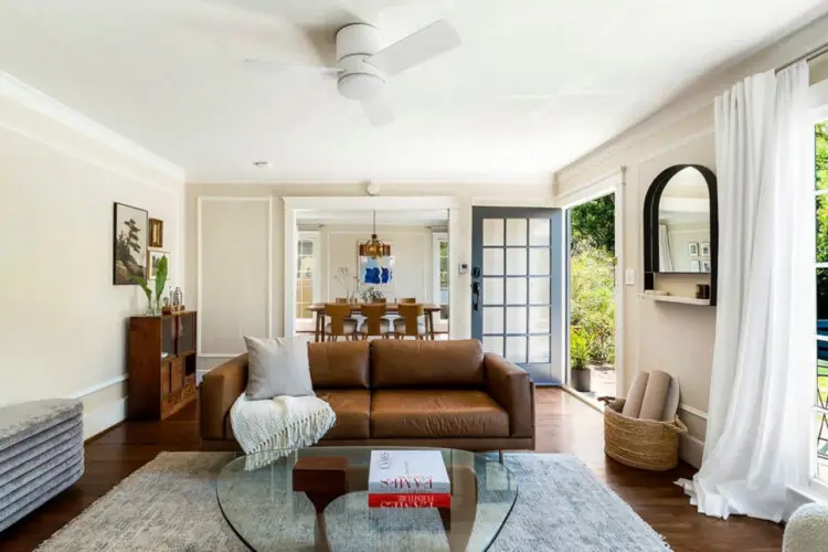 Living area with leather sofa, glass coffee table, and view of dining area at Charming Walk Street Hideaway in Venice Beach by Open Air Homes.