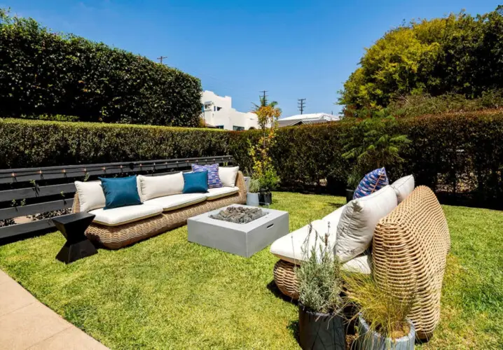 Outdoor seating area with wicker furniture and fire pit in garden at Charming Walk Street Hideaway in Venice Beach by Open Air Homes.