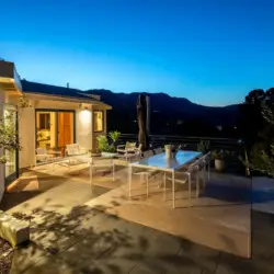 Outdoor patio area with dining table, chairs, and view of surrounding landscape at Hillside Hideaway in Topanga Canyon by Open Air Homes.