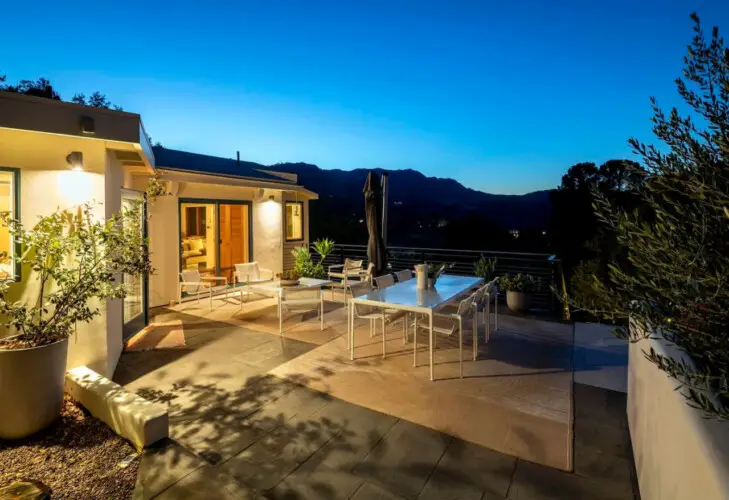 Outdoor patio area with dining table, chairs, and view of surrounding landscape at Hillside Hideaway in Topanga Canyon by Open Air Homes.