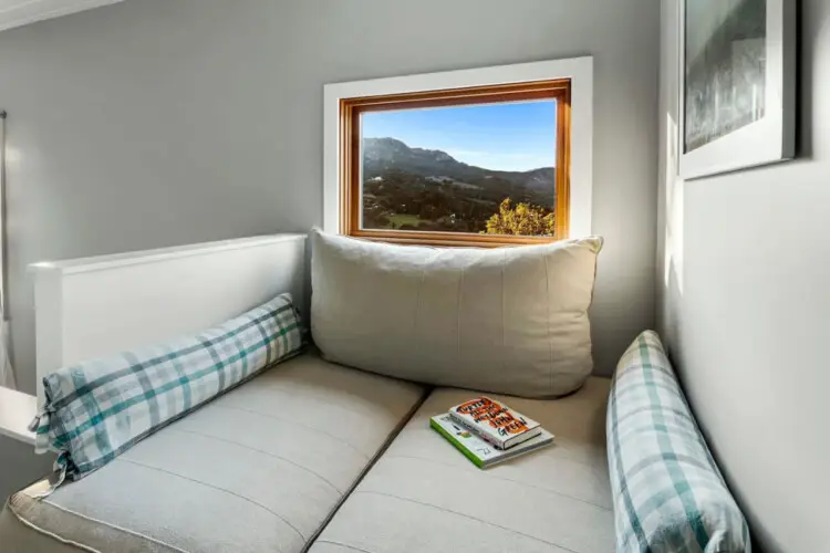 Reading nook with cushioned seat, pillows, and a book at Hillside Hideaway in Topanga Canyon.