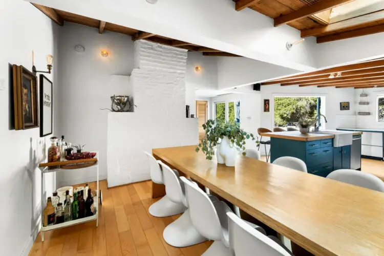 Dining area with wooden ceiling, table, and white chairs at Hillside Hideaway in Topanga Canyon - by Open Air Homes