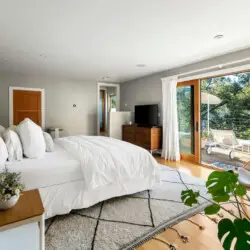 Bedroom with large bed, rug, and sliding glass door leading to outdoor area at Hillside Hideaway in Topanga Canyon by Open Air Homes.