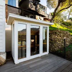 Outdoor area with glass-enclosed sauna and wooden deck at Hillside Hideaway in Topanga Canyon by Open Air Homes.