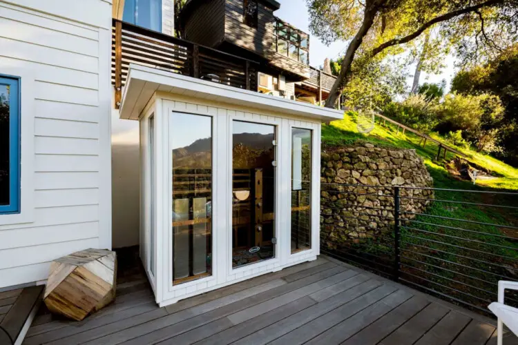 Outdoor area with glass-enclosed sauna and wooden deck at Hillside Hideaway in Topanga Canyon by Open Air Homes.