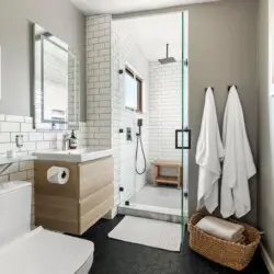 Modern bathroom with glass shower, white tiles, and wooden accents at Hillside Hideaway in Topanga Canyon by Open Air Homes.