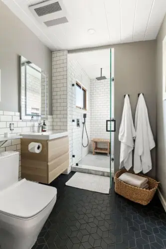 Modern bathroom with glass shower, white tiles, and wooden accents at Hillside Hideaway in Topanga Canyon by Open Air Homes.