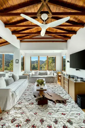 Living room with wooden ceiling, fireplace, and TV at Hillside Hideaway in Topanga Canyon - by Open Air Homes