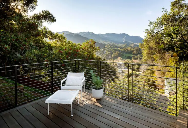 Balcony with white chair and ottoman overlooking scenic hills at Hillside Hideaway in Topanga Canyon by Open Air Homes.