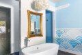 Bathroom with a freestanding bathtub, gold-framed mirror, and decorative wall at Ocotillo, Palm Springs