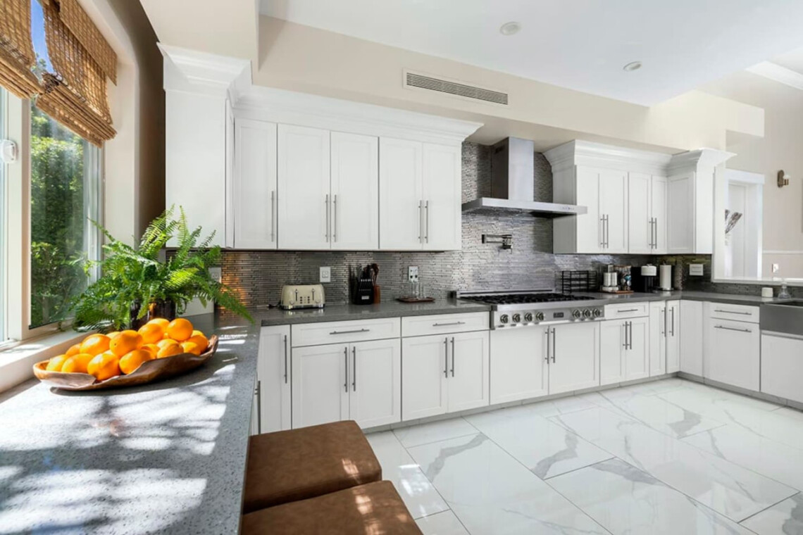 Kitchen with white cabinets, stainless steel range, and large window at Ocotillo, Palm Springs