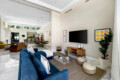 Living room with shuffleboard table, blue sofa, and wall-mounted TV at Ocotillo, Palm Springs