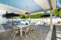 Outdoor dining area with a table and chairs under an awning by the pool at Ocotillo, Palm Springs