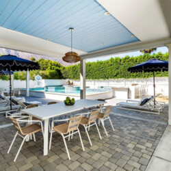 Outdoor dining area with a table and chairs under an awning by the pool at Ocotillo, Palm Springs