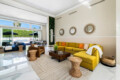 Living room with yellow sofa, coffee table, and large windows at Ocotillo, Palm Springs