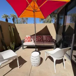 Outdoor seating area with chairs, table, and umbrella at Sunset Sands in Palm Springs by Open Air Homes