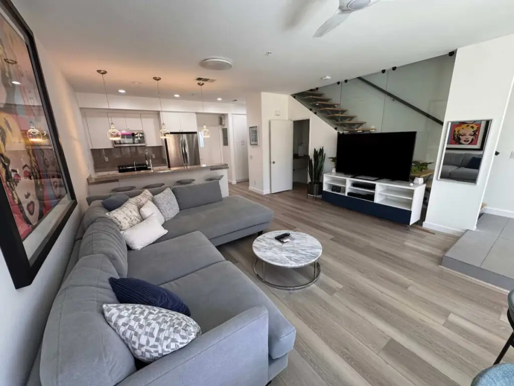 Sunset Sands by Open Air Homes - Modern + Pool 8 Modern living room with sofa and kitchen view in City Lights Loft – Open Air Homes.
