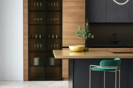 Modern kitchen with breakfast bar, green stool, and glass cabinet with dishes.