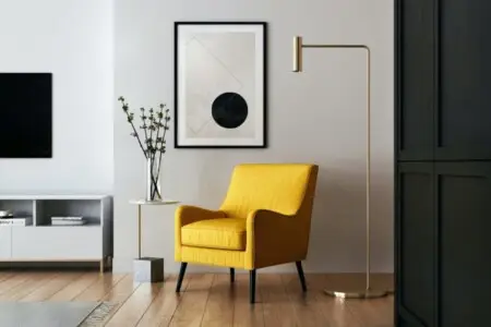 Living room with a yellow armchair, a floor lamp, a side table with a plant, and a framed artwork on the wall.