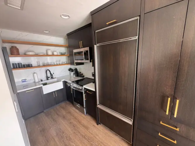 Kitchen area with sink, stove, and shelves at Malibu Breeze.