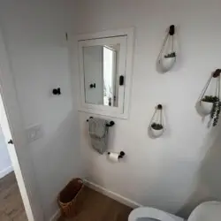 Bathroom with mirror, towel rack, and plants at Malibu Breeze.