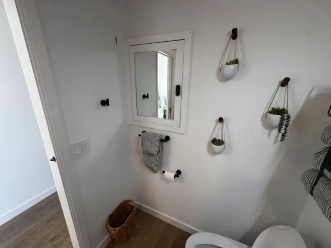 Bathroom with mirror, towel rack, and plants at Malibu Breeze.