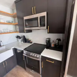 Kitchen area with stove, microwave, and shelves at Malibu Breeze.