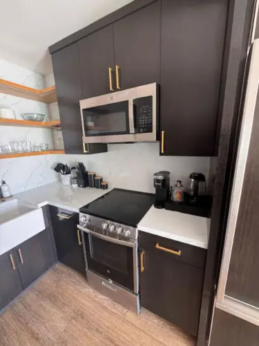 Kitchen area with stove, microwave, and shelves at Malibu Breeze.