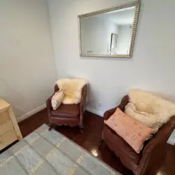 Cozy seating area with two chairs and a mirror at Beverly Grove Tudor Family Home - by Open Air Homes.