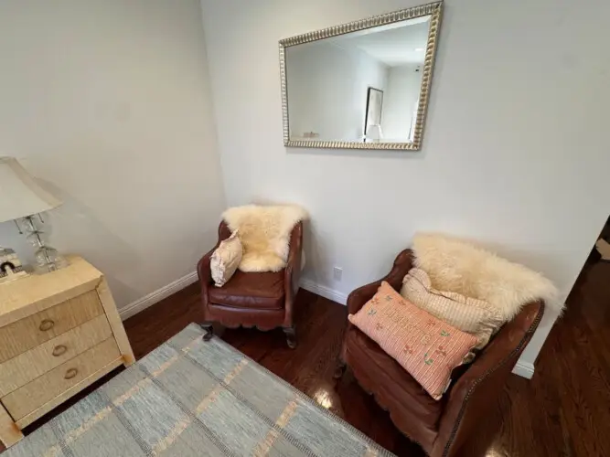 Cozy seating area with two chairs and a mirror at Beverly Grove Tudor Family Home - by Open Air Homes.