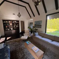 Living room with vaulted ceiling, striped sofa, and bookshelf at Beverly Grove Tudor Family Home - by Open Air Homes.